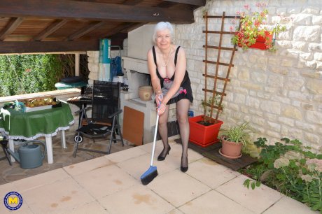 Horny granny lifts her sexy skirt to play with her beaver in the garden