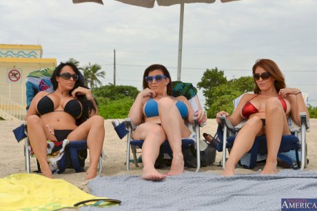 Three busty beach babes pull aside bikini tops to flaunt big tits by the water