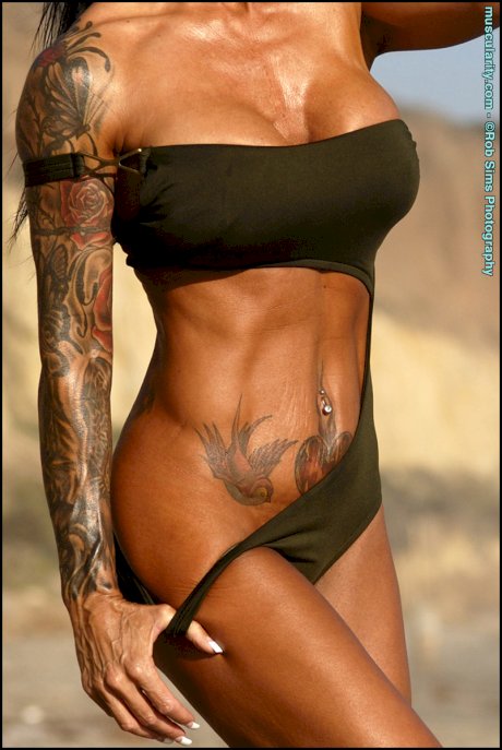 Brunette bodybuilder Ava Jordan frees her fake tits from swimwear on a beach