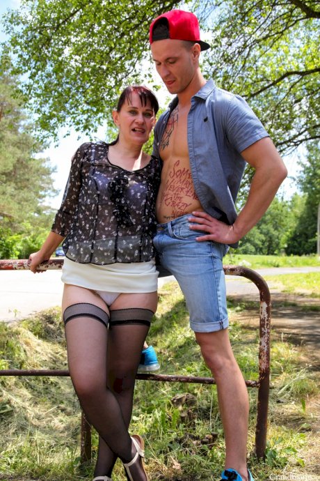 Skinny granny Vicky strips to stockings and rides a young guy's dick in nature
