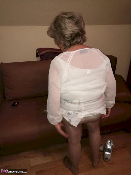 Mature lady exposes her large tits while having a smoke in pantyhose