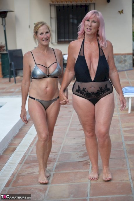 Mature BBW Melody and her girlfriend walk hand in hand by a pool in swimwear