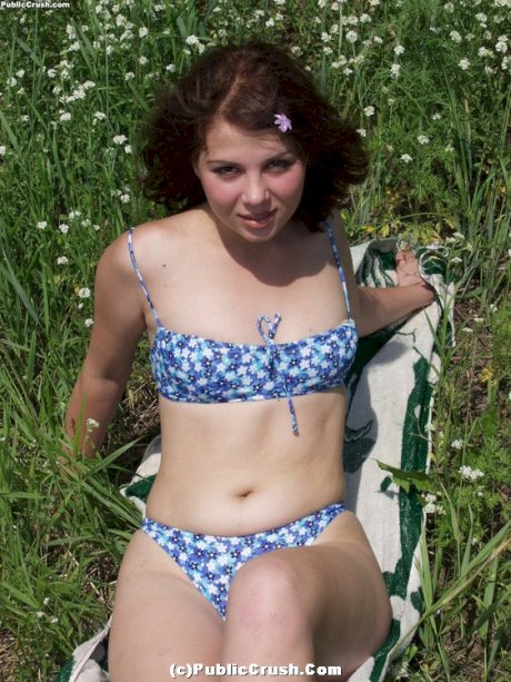 Young looking girl takes off her bikini to go naked amid wildflowers