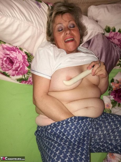 Horny older woman licks her nipple before dildoing her hairy pussy