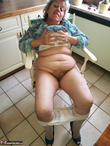 Horny granny Caro sticks a banana inside her natural pussy on kitchen chair