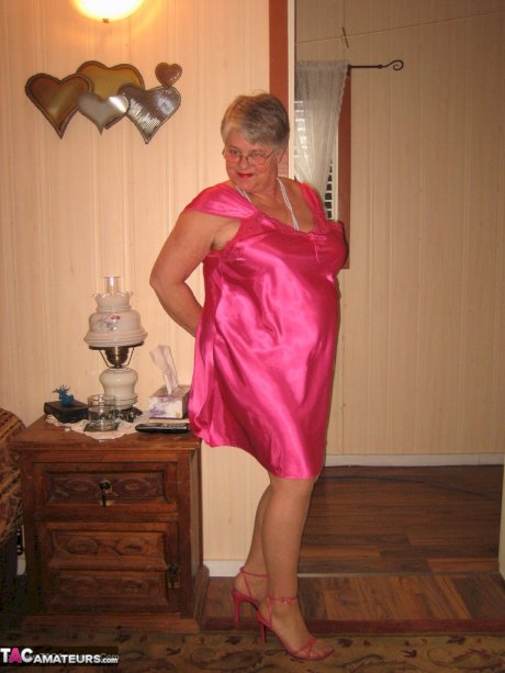 Silver haired nan Girdle Goddess pulls her hose down around her knees on a bed