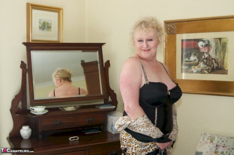 Blonde granny admires herself in a mirror while wearing lingerie and nylons