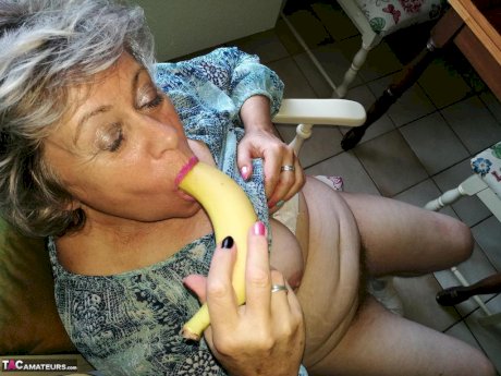 Horny granny Caro sticks a banana inside her natural pussy on kitchen chair