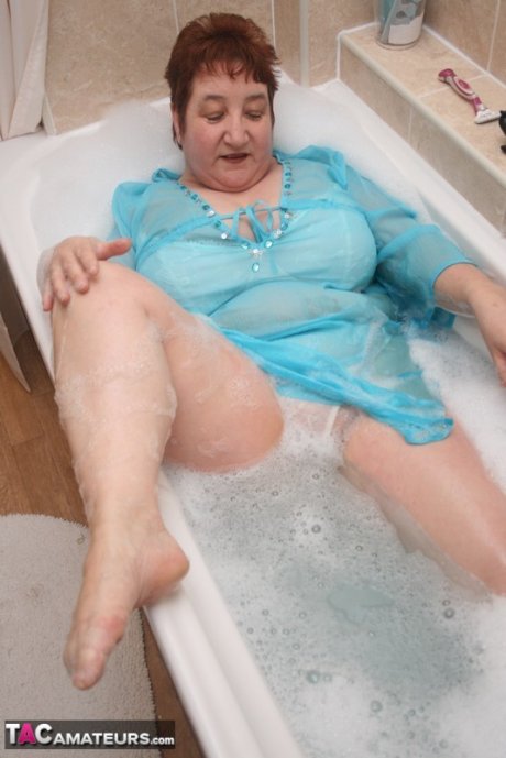 Redhead nan Kinky Carol parks her fat figure in a tub while fully clothed