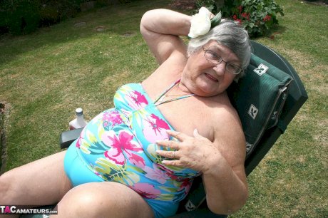 Naughty amateur granny Libby inserting a bottle in her fat pussy in the garden