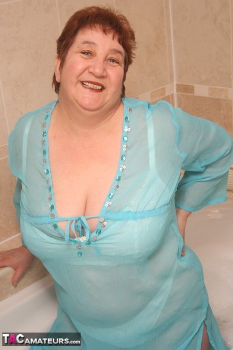 Redhead nan Kinky Carol parks her fat figure in a tub while fully clothed