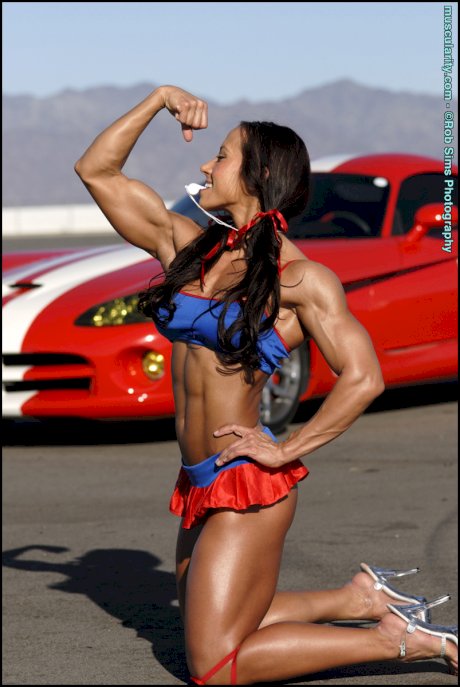 Bodybuilder Patricia Beckman flexes her muscles in front of a sports car