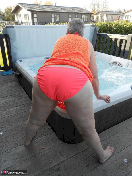 Fat nan bares her boobs while in a patio hot tub before getting naked on a bed