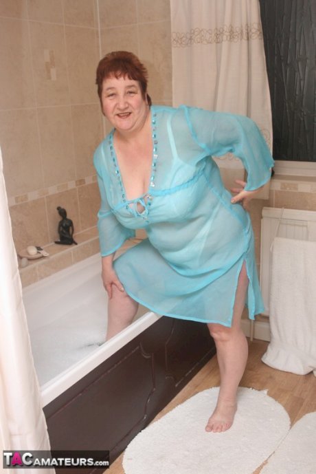 Redhead nan Kinky Carol parks her fat figure in a tub while fully clothed