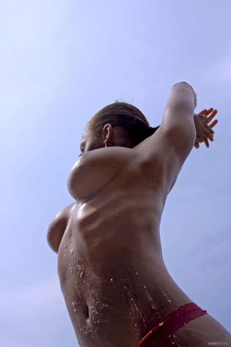 Ebony girl Tierra exposes her big natural tits while stripping in the sea