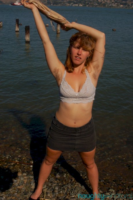 Saucy young slut Lilah strips by the water and unveils her hairy body