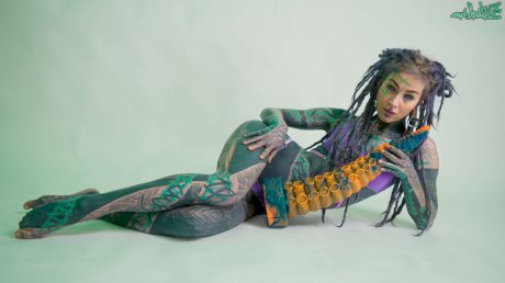 Heavily tattooed girl Anuskatzz holds a couple of taintacle toys in the nude