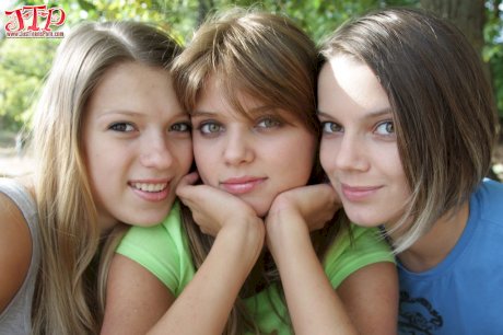 Three young looking girls gets naked on a wooden bench in the countryside