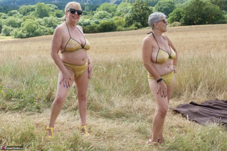 Old lesbians catch rays on their large breasts while sunbathing in a field