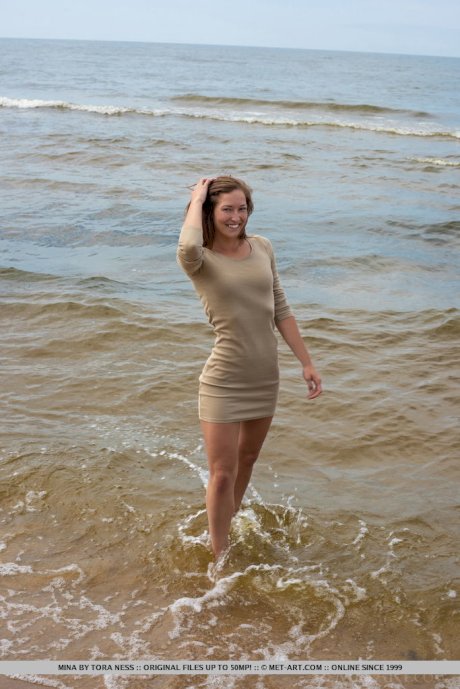 Tall teen Mina hangs wet clothes to dry while posing nude on a beach