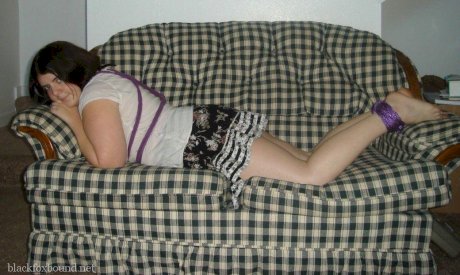Overweight girl has her hands tied behind her back while her ankles are bound
