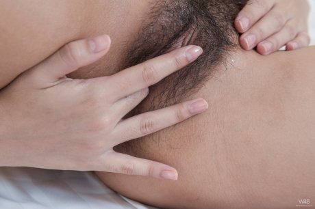 Asian honey with hot big tits Kahlisa fingers her bushy beaver on a bed