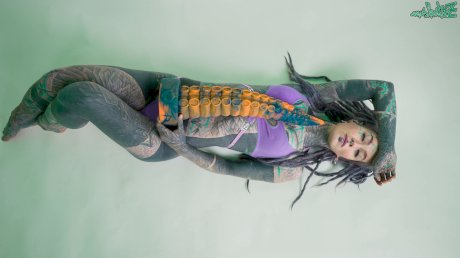 Heavily tattooed girl Anuskatzz holds a couple of taintacle toys in the nude