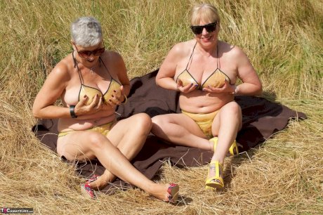 Old lesbians catch rays on their large breasts while sunbathing in a field
