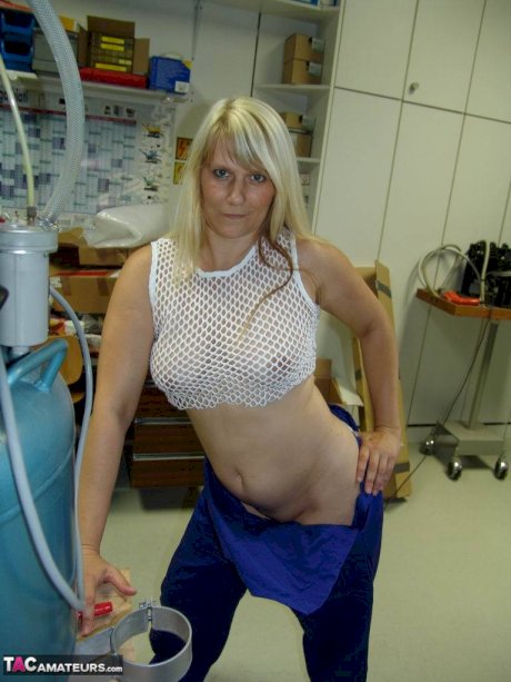 Mature blonde removes her overall before masturbating in workshop