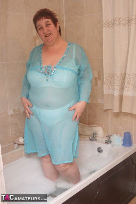 Redhead nan Kinky Carol parks her fat figure in a tub while fully clothed