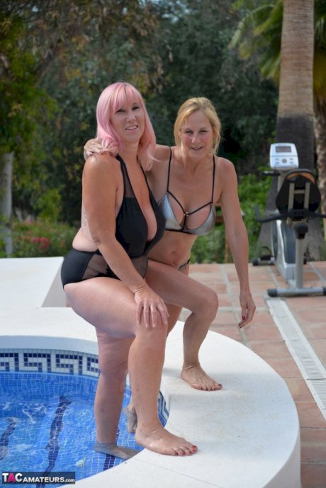 Mature BBW Melody and her girlfriend walk hand in hand by a pool in swimwear