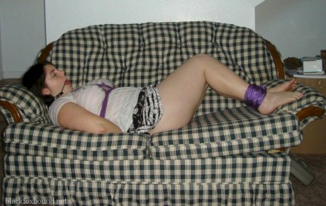 Overweight girl has her hands tied behind her back while her ankles are bound
