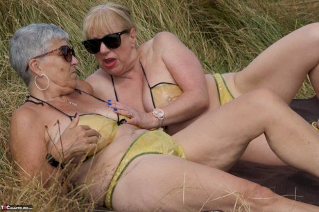 Old lesbians catch rays on their large breasts while sunbathing in a field