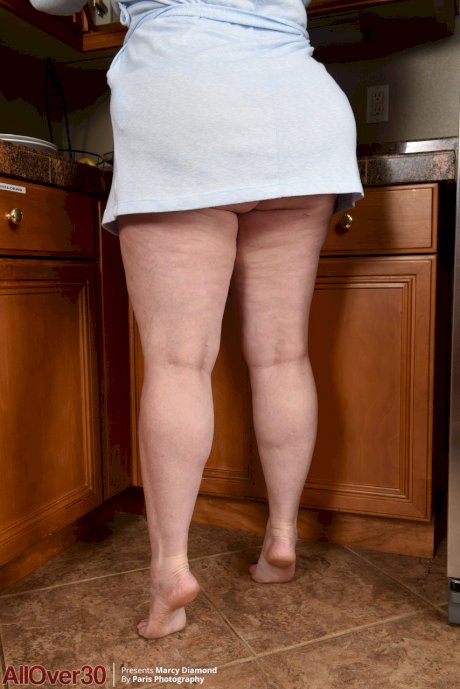 Chubby redhead Marcy Diamond reveals her big ass and big tits in the kitchen
