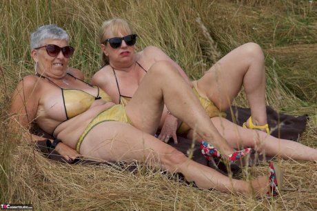 Old lesbians catch rays on their large breasts while sunbathing in a field