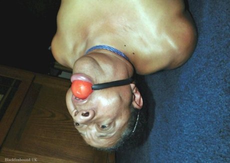 Overweight black woman Trixie struggles against a ball gag while hogtied