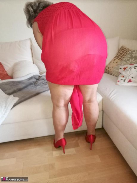 Horny oma Caro hikes up long red dress to spread her hairy vagina