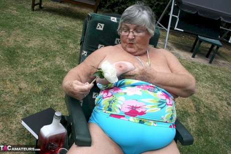 Naughty amateur granny Libby inserting a bottle in her fat pussy in the garden