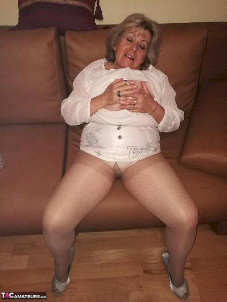 Mature lady exposes her large tits while having a smoke in pantyhose