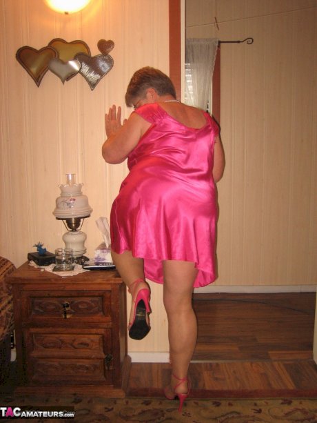 Silver haired nan Girdle Goddess pulls her hose down around her knees on a bed