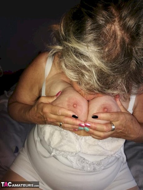 Naughty granny exposes her boobs while changing attire in nylons and heels