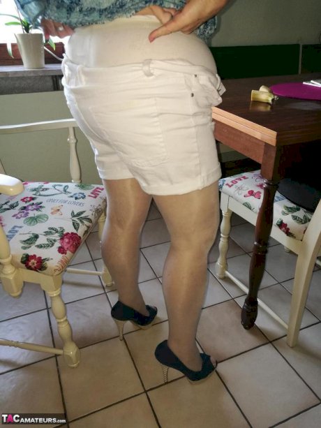Horny granny Caro sticks a banana inside her natural pussy on kitchen chair