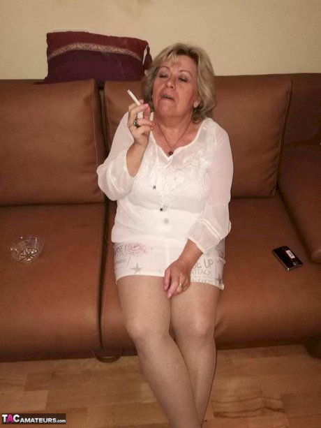 Mature lady exposes her large tits while having a smoke in pantyhose