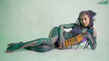 Heavily tattooed girl Anuskatzz holds a couple of taintacle toys in the nude