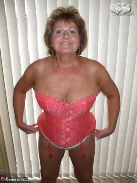 Older amateur Busty Bliss licks her lips while working free of sexy lingerie