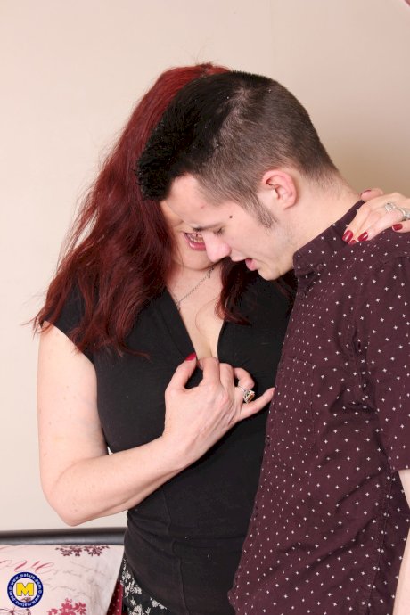 Redhead mature housewife Christina seduces and fucks a young boy on a bed