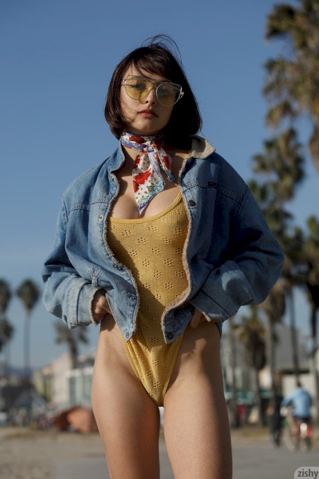 Adorable teen Basil Navas poses on the beach in yellow see-through bodysuit