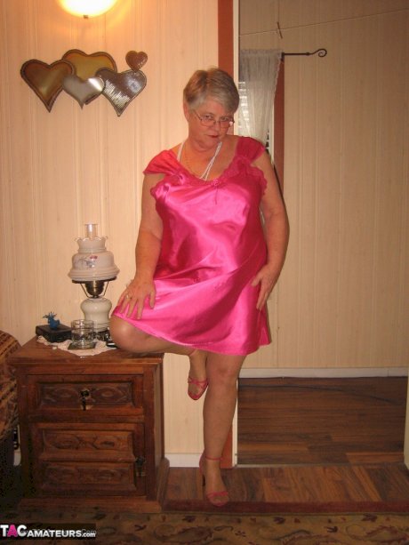 Silver haired nan Girdle Goddess pulls her hose down around her knees on a bed