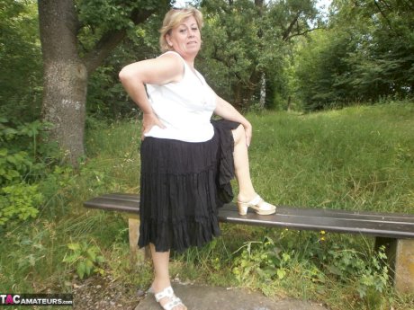Mature amateur whore Caro masturbating on the bench in the woods