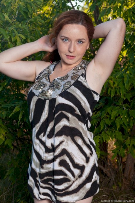 Chunky redhead Elouisa uncoves her large tits as she gets naked in the bushes